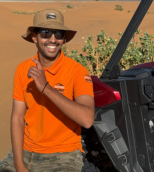 Guía de Sahara Buggy sonriendo junto a un buggy en el desierto de Merzouga durante una jornada de rutas.