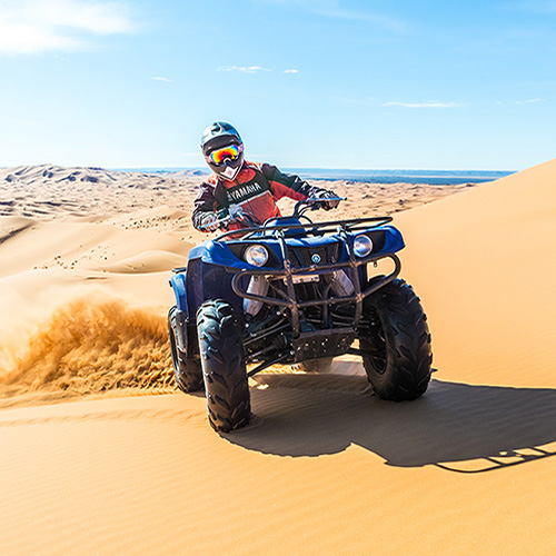 Participant riding a quad over the dunes of Erg Chebbi in Merzouga during an accessible and safe experience with Sahara Buggy.