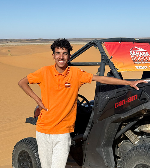 Guía del equipo de Sahara Buggy de pie junto a un buggy en el desierto de Merzouga, preparado para una ruta.