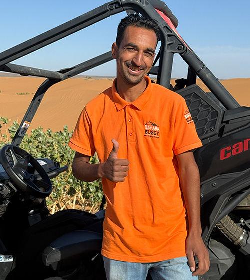 Guía del equipo de Sahara Buggy posando junto a un buggy en el desierto de Merzouga antes de una ruta.