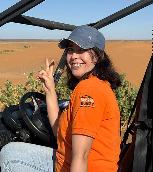 Equipo local del desierto del Sahara: Guía del equipo de Sahara Buggy sonriendo mientras conduce un buggy en las dunas del desierto de Merzouga.